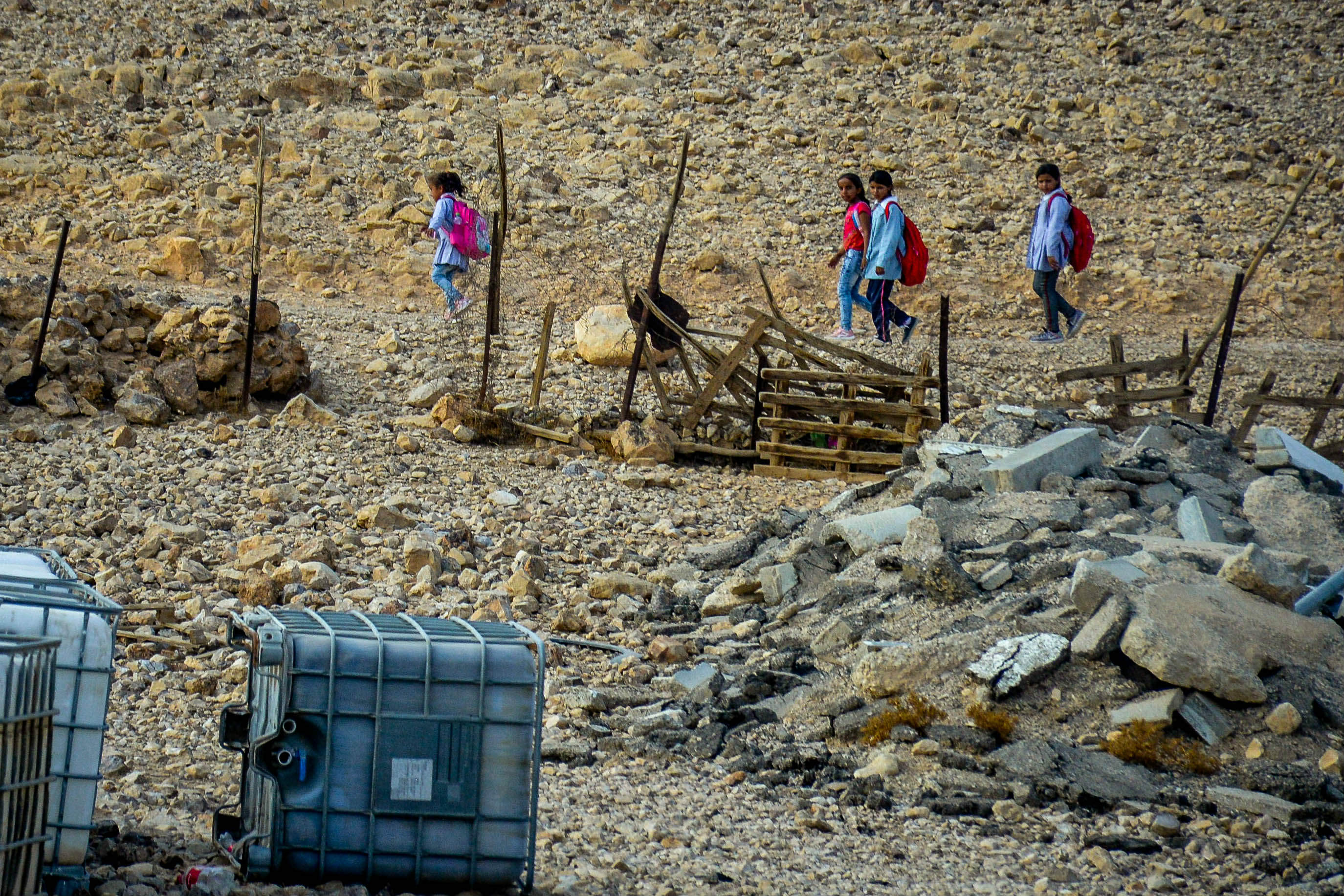 Palestinian school from the Al Awjah Bedouin community walk by empty water reserves (MEE/Qassam Muaddi)