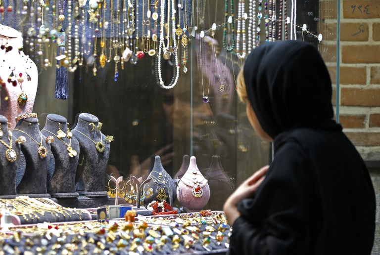 A woman glances at jewellery displayed in a shop widow in the Iranian capital Tehran's grand bazar on November 3, 2018. 