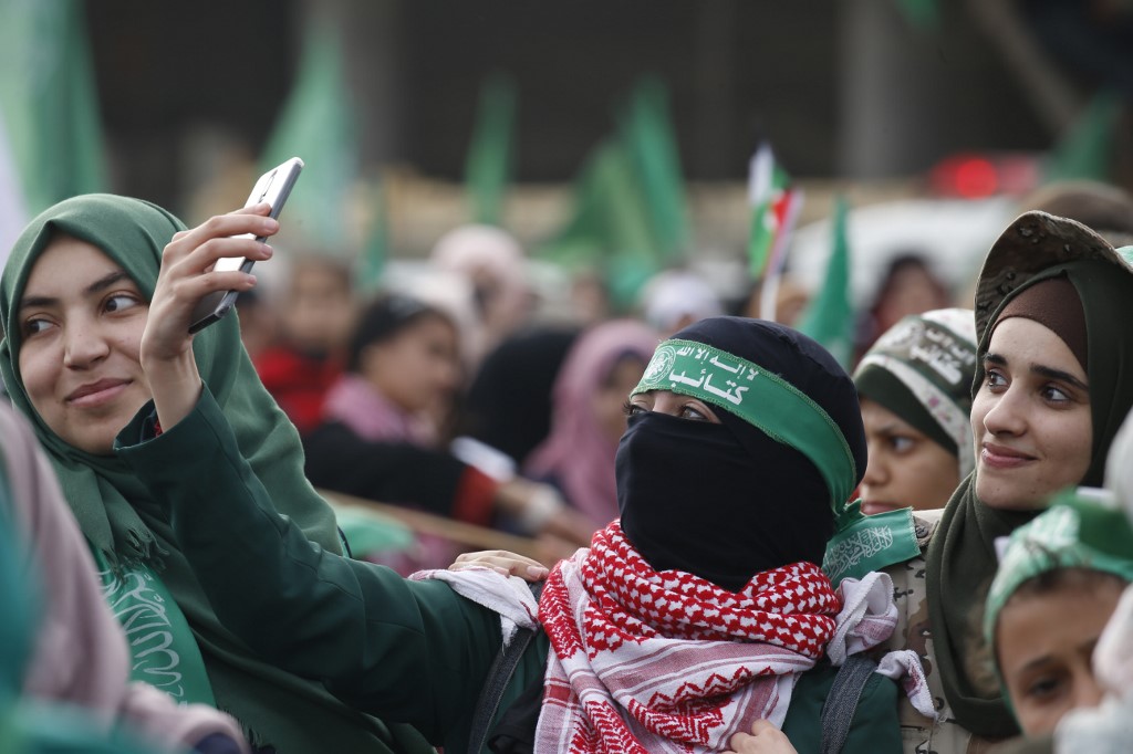 Une femme prend un selfie alors que les Palestiniens assistent à un rassemblement marquant le 31e anniversaire de la fondation du Hamas, à Gaza, le 16 décembre (AFP)