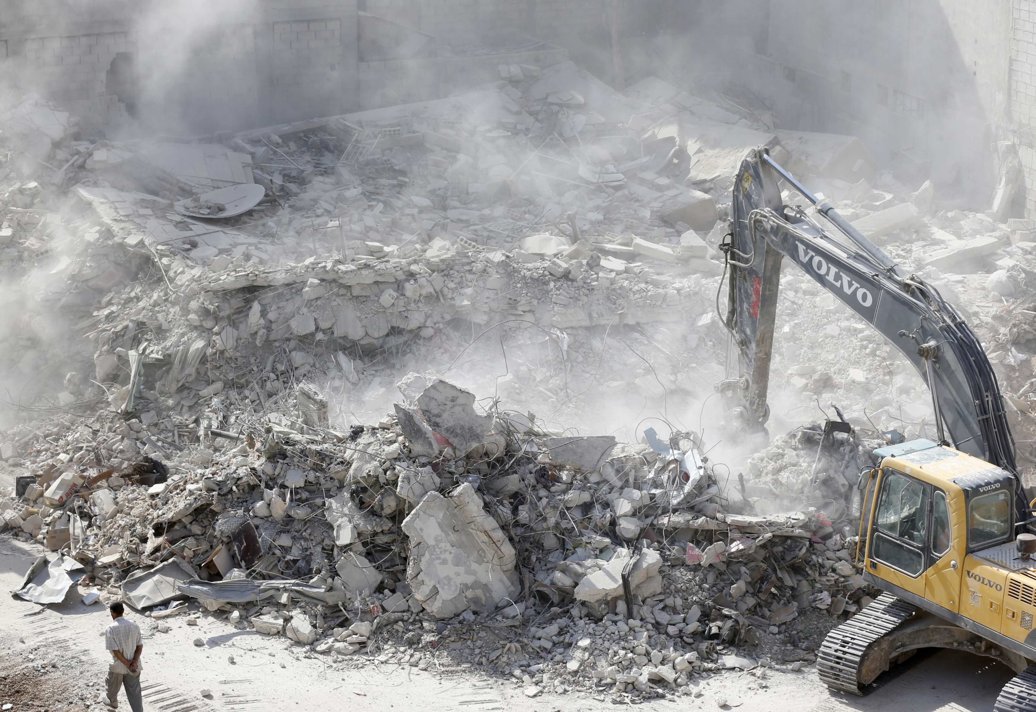 Un bulldozer déblaie les décombres de bâtiments détruits à Harasta, en périphérie de la capitale syrienne Damas, en juillet 2018 (AFP)