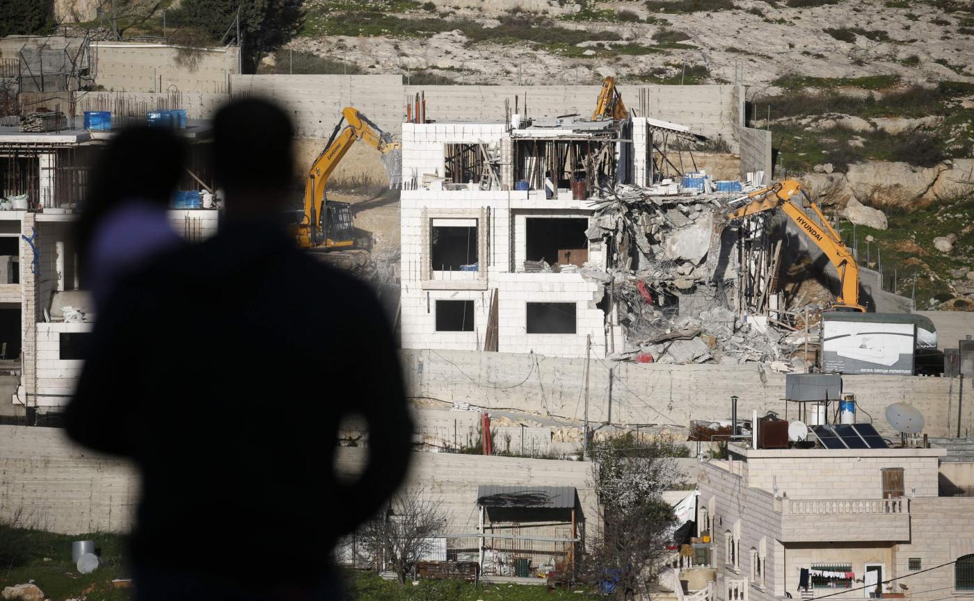 Des pelles hydrauliques démolissent un bâtiment palestinien au nord de la ville d’Hébron, en Cisjordanie occupée, en février 2018 (AFP)