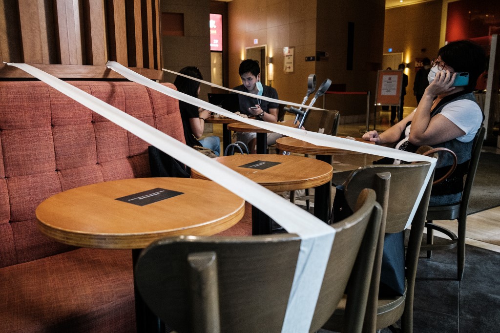 Customers sit in a cafe that has masking tape on every other table to enforce social distancing in Hong Kong on 21 April (AFP)