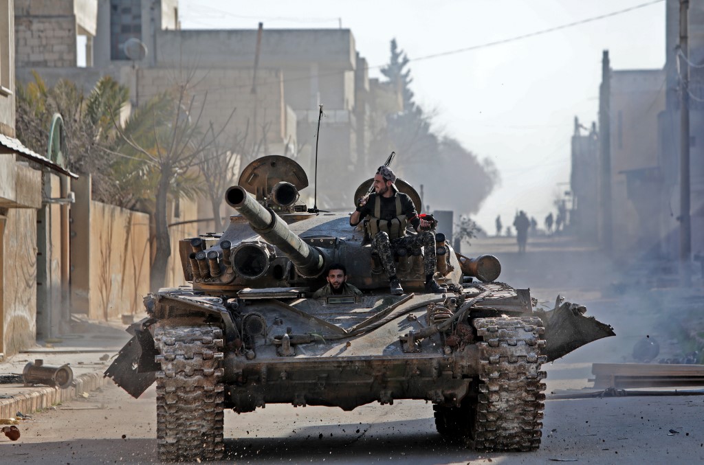 Syrian rebels ride a tank in eastern Idlib province on 27 February (AFP)