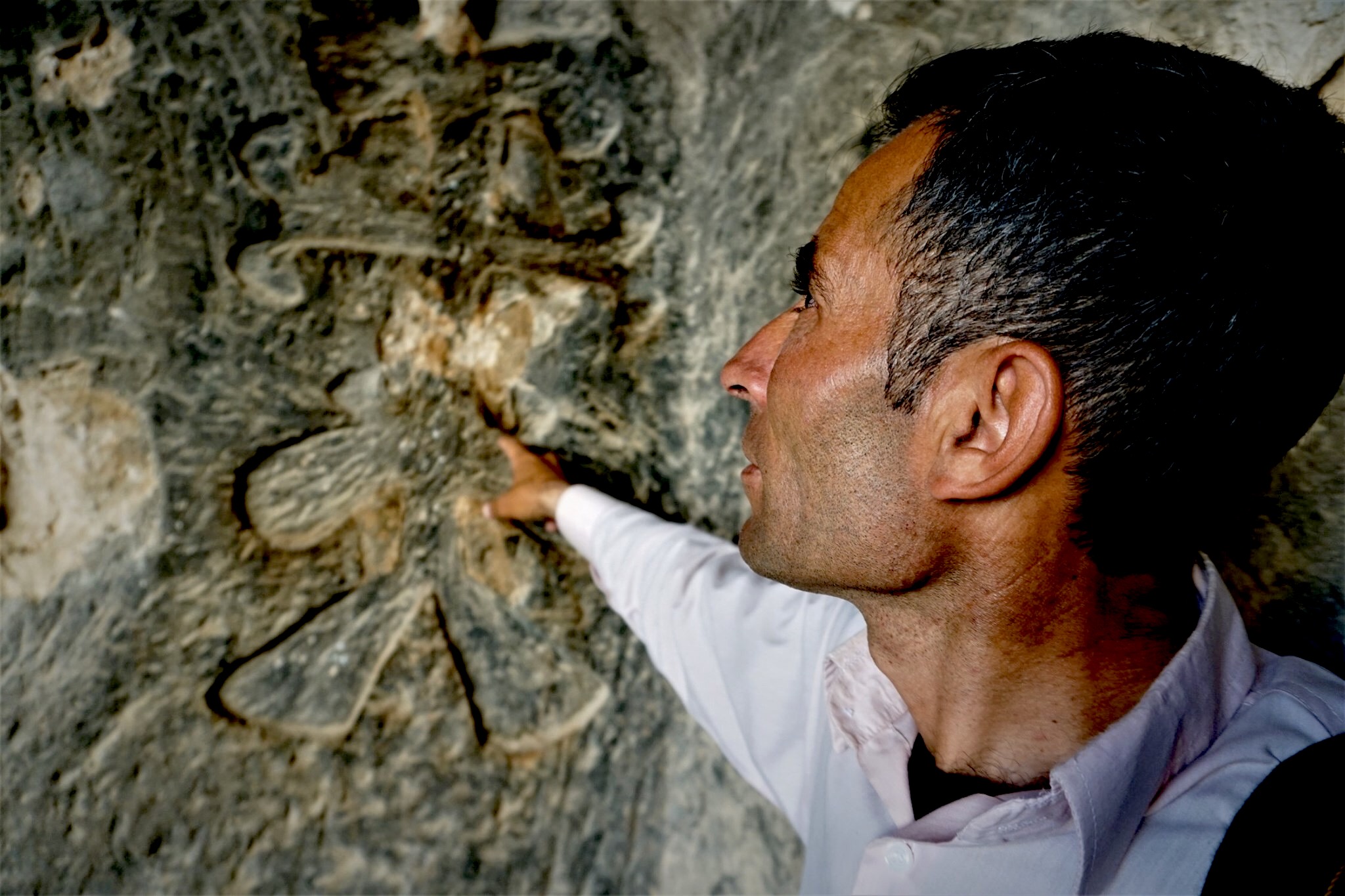 Shepherd Ali points to a leaf-like Christian cross carved on the wall inside one of the caves that would sink under the artificial lake. (Nimet KIRAC/ MEE)