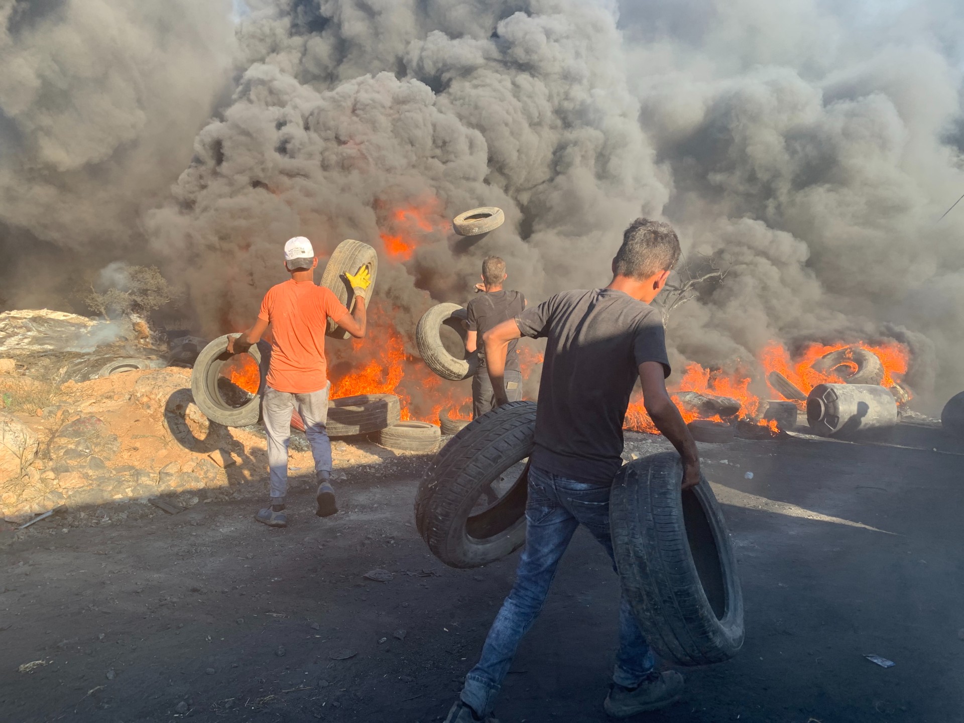 Palestinian youths set fire to tyres during a protest against an illegal Israeli settlement outpost in Beita (MEE/Shatha Hammad)