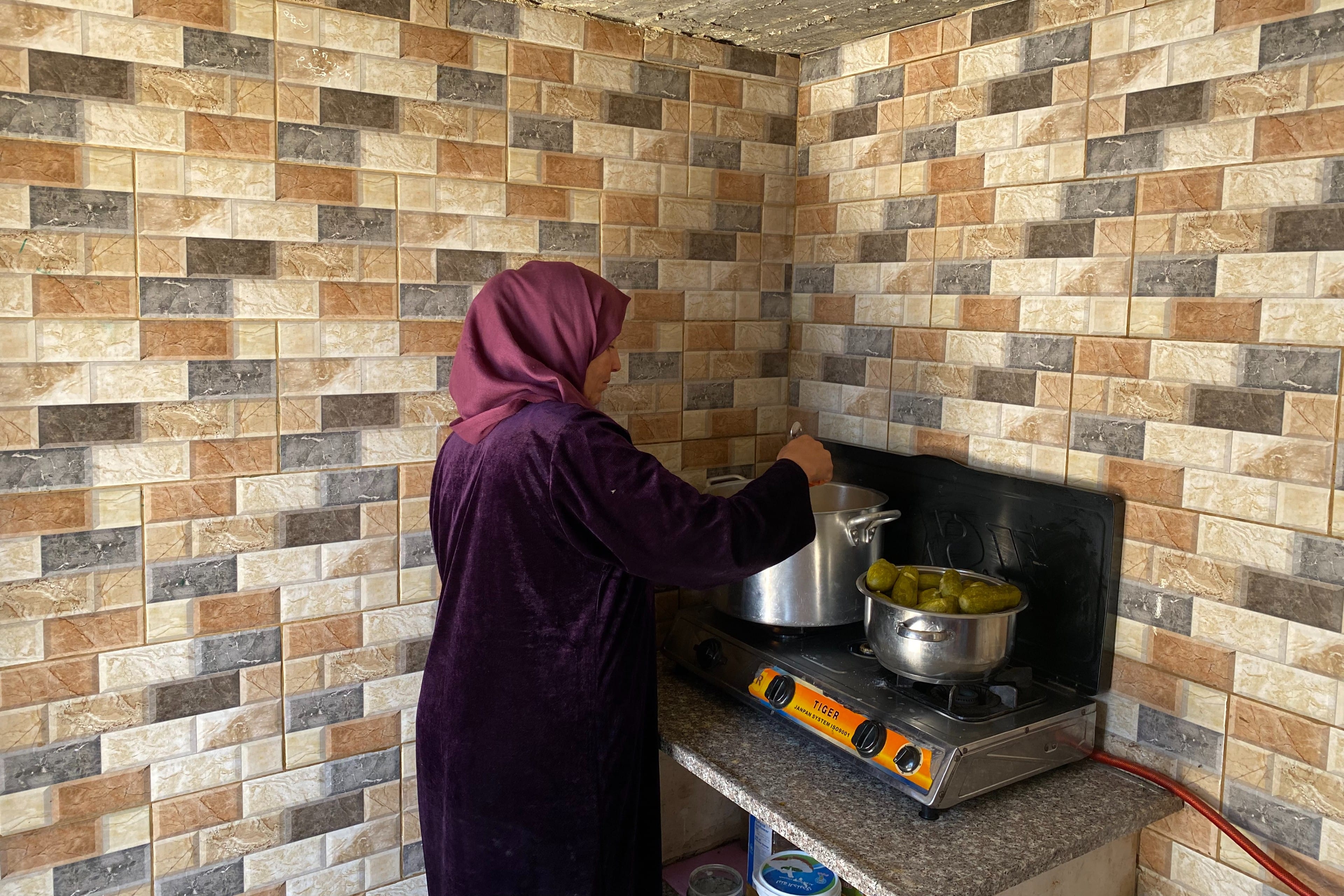 Laila Mo'nes preparing lunch for her children in the Israeli-occupied West Bank hamlets of Masafer Yatta on 19 June 2022. (MEE/Shatha Hammad)