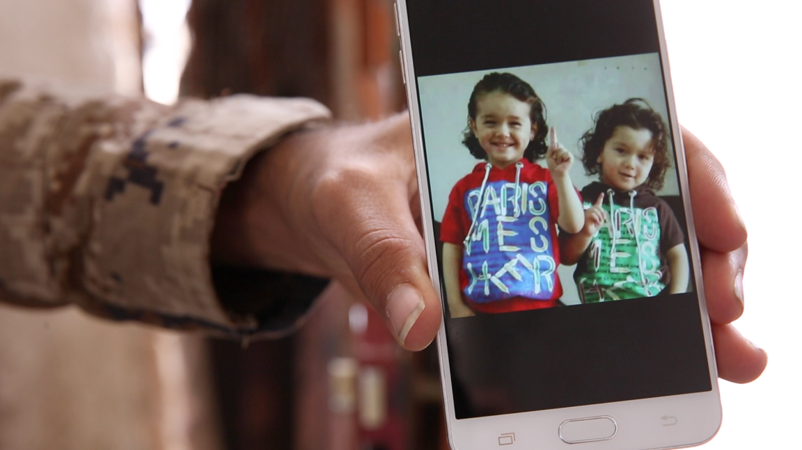 Un combattant des FDS montre sur son téléphone portable une photo d’enfants de membres français de l’EI faisant le symbole de l’allégeance au groupe (MEE/Stéphane Kenech)