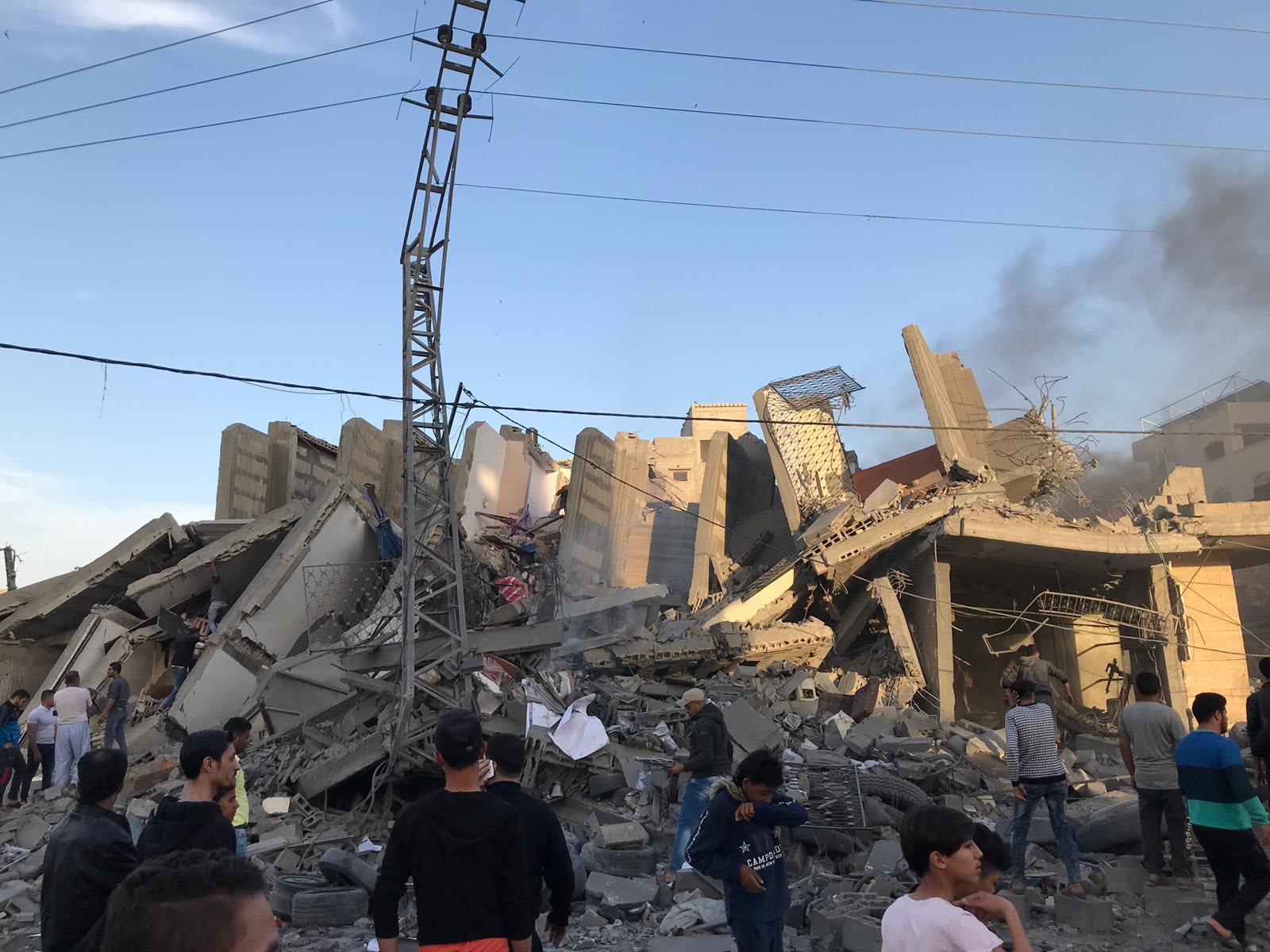 Palestinians view the damage after Israeli strikes level the Abu Qamar building in Gaza City (MEE)