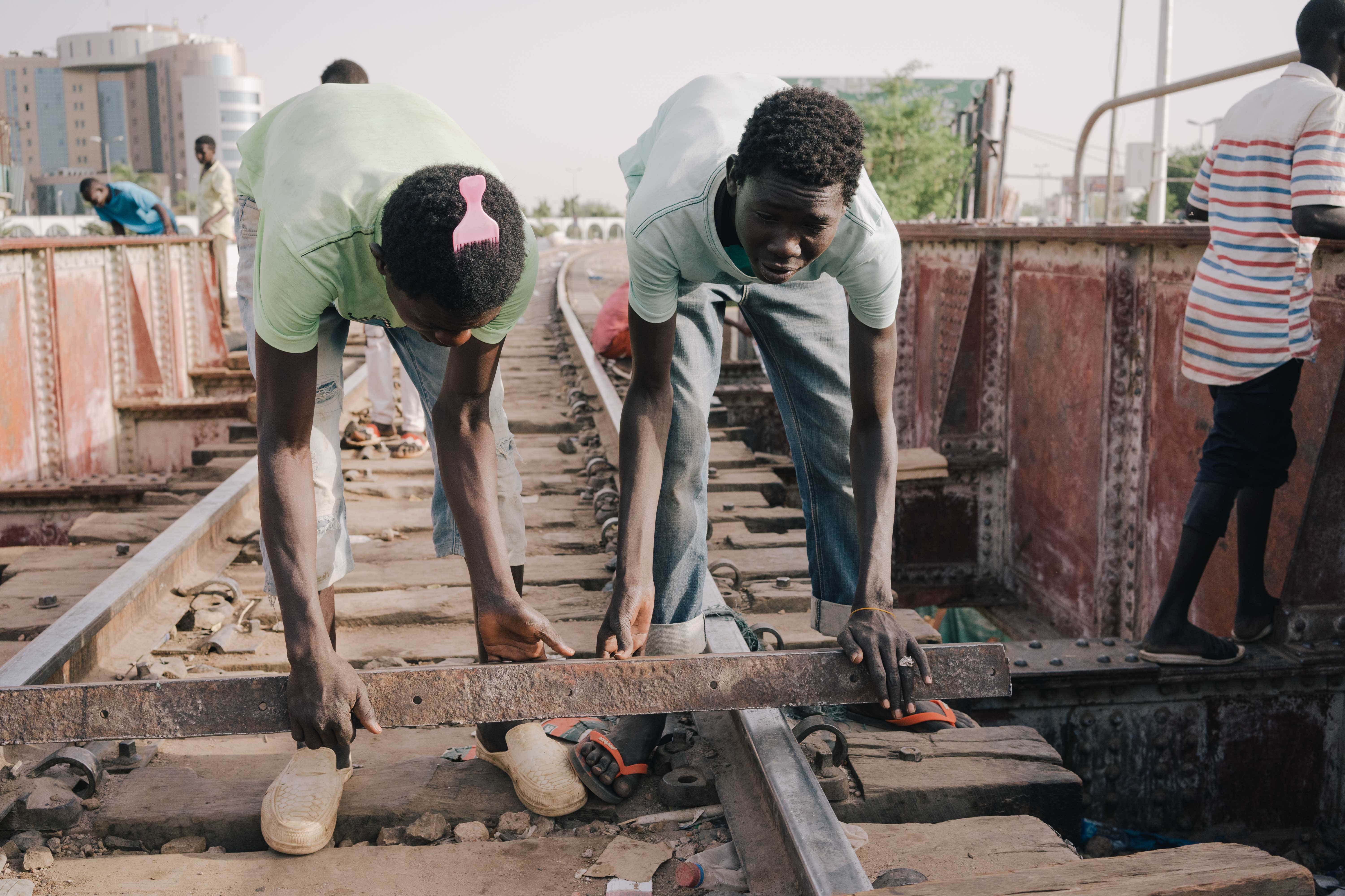 De jeunes Soudanais battent le rythme sur un pont de chemin de fer en métal à Khartoum (MEE/Kaamil Ahmed)