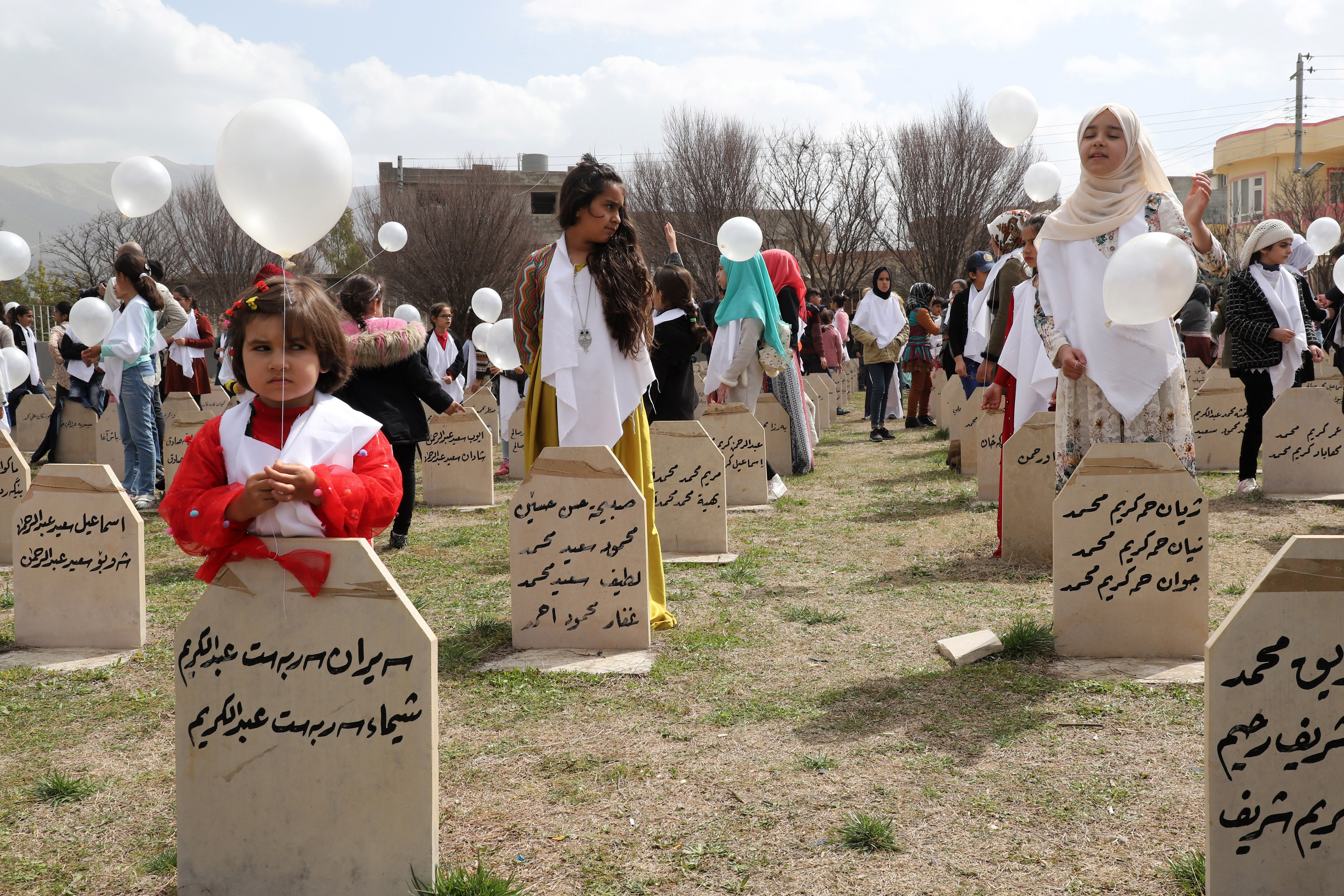 Iraqi-Kurds visit a grave site in Halabja near the monument for victims of the Halabja gas massacre that killed some 5,000 people as they mark the 31th anniversary of the attack (AFP)