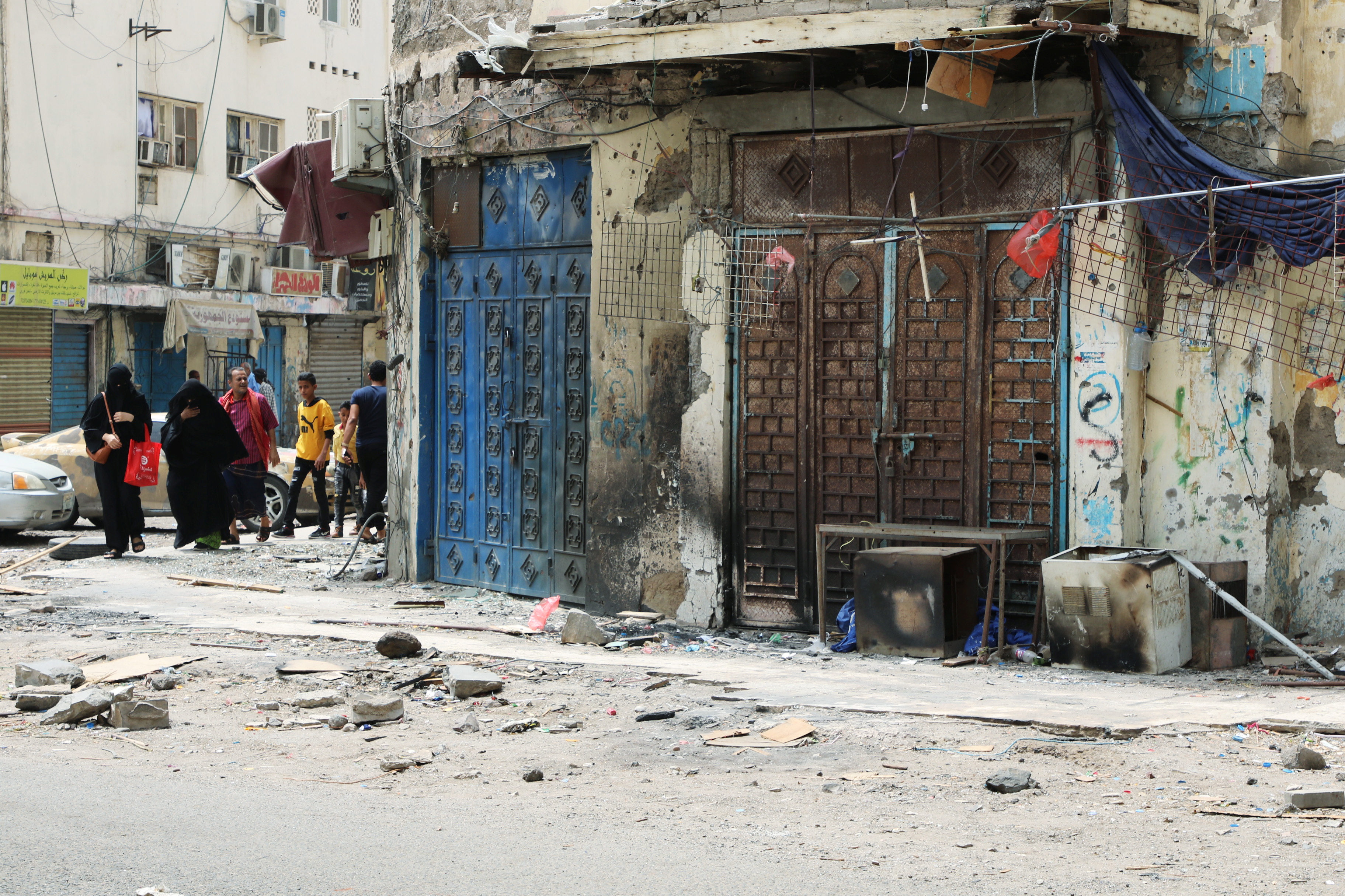 Yemenis walk past shops damaged during clashes in Aden (Reuters)