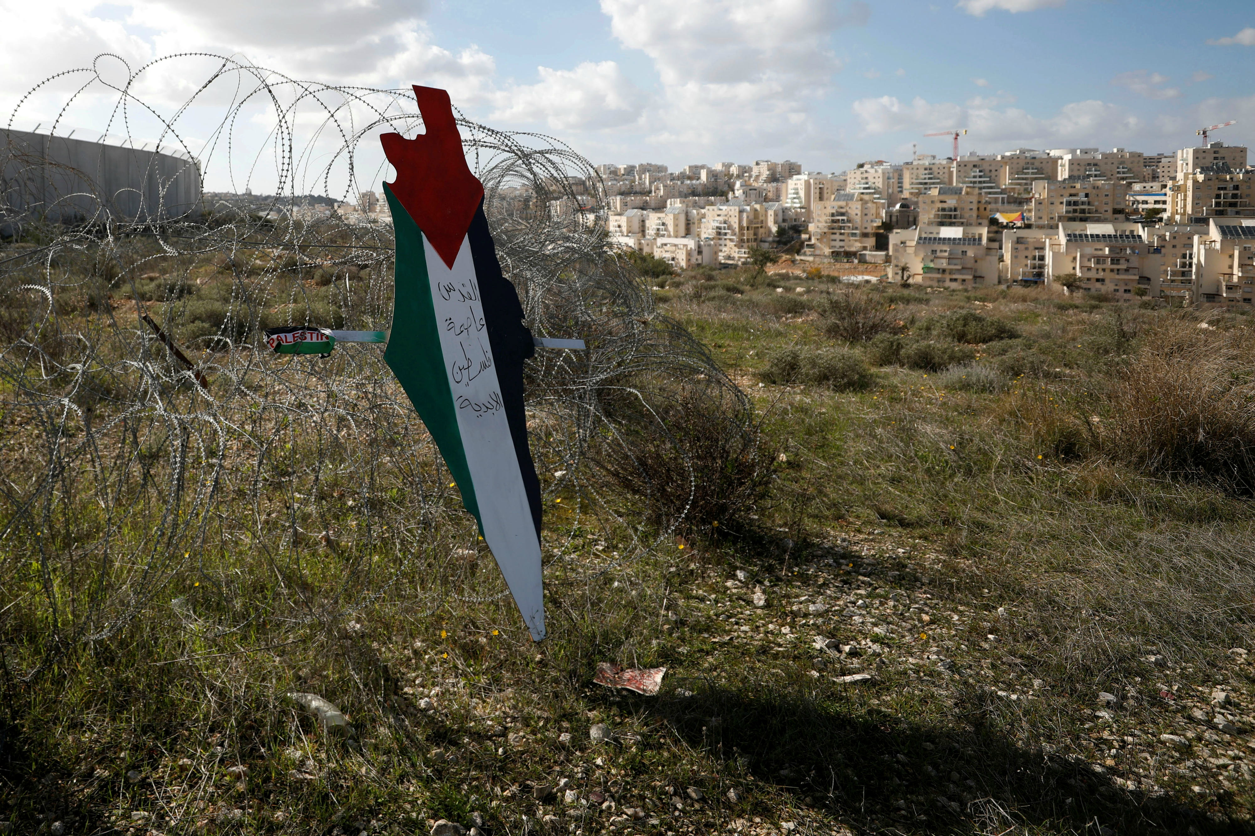 A map with the colours of the Palestinian flag reading ‘Jerusalem is the eternal capital of Palestine’ is seen near a Jewish settlement in the occupied West Bank (Reuters)