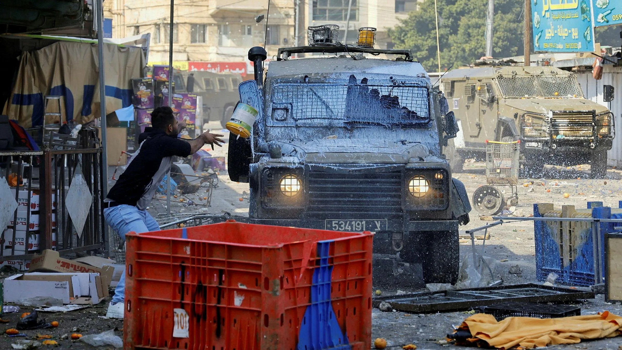 Palestinian youths hurl paint and rocks at an Israeli military vehicle during a raid in Nablus on 22 February 2023 (Reuters)  