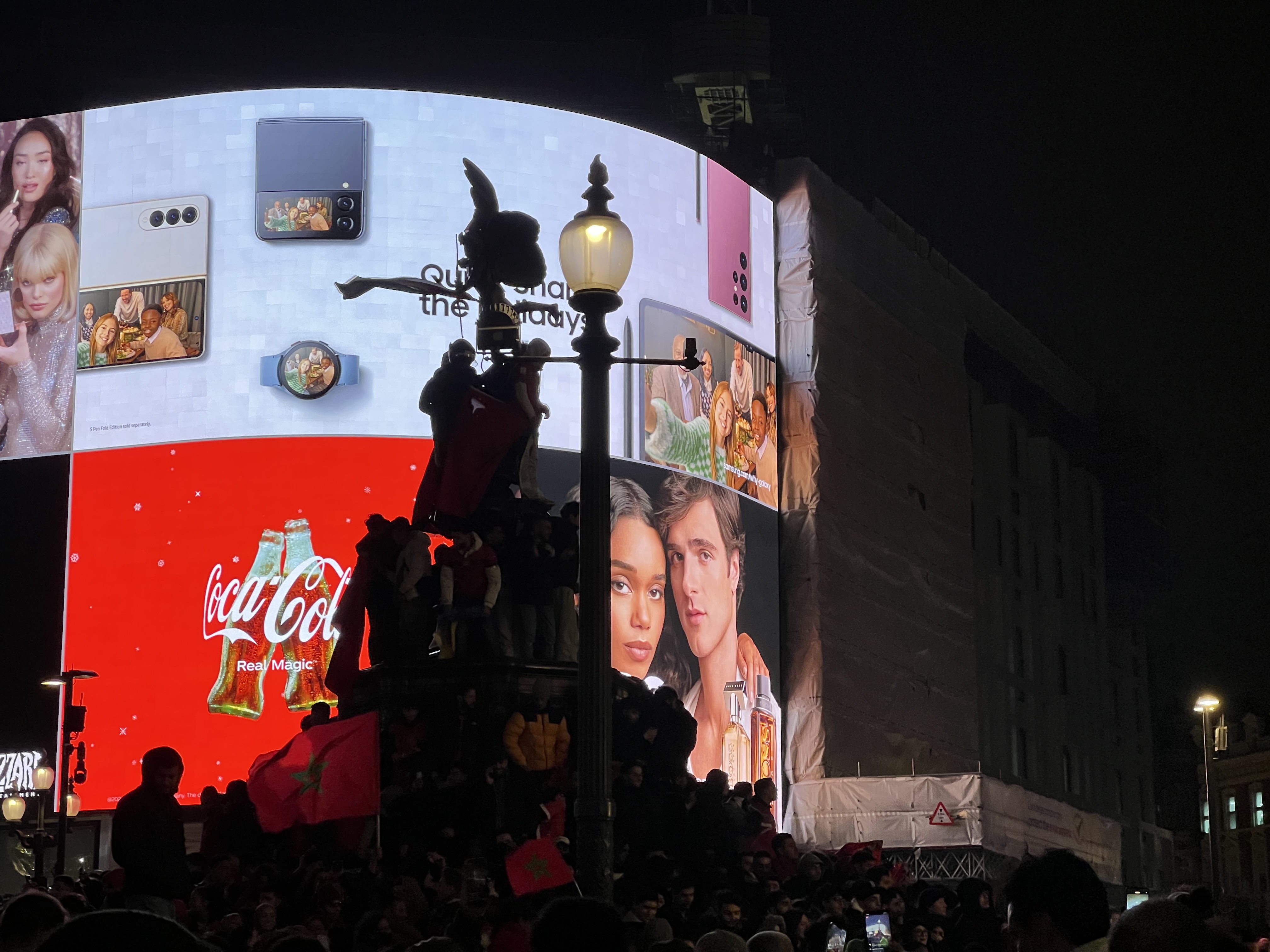 Crowds climbed on top of the Eros statue to place Moroccan flags in London’s Piccadilly Circus (MEE/Areeb ULLAH)