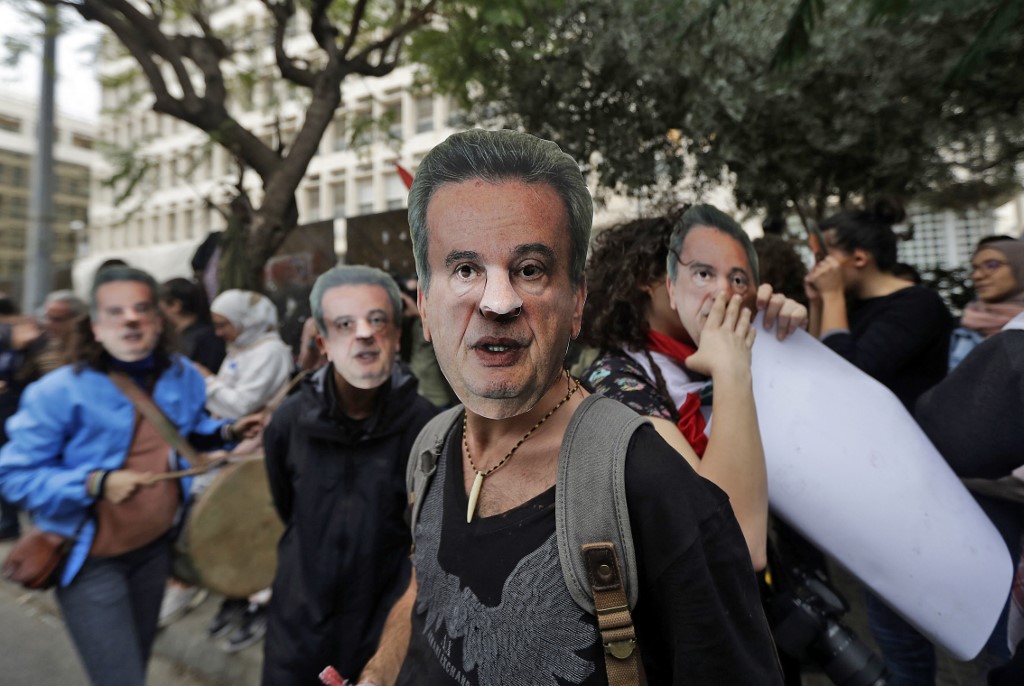 Anti-government protesters wear masks of Riad Salameh outside Central Bank headquarters in Beirut, in November 2019 (AFP)