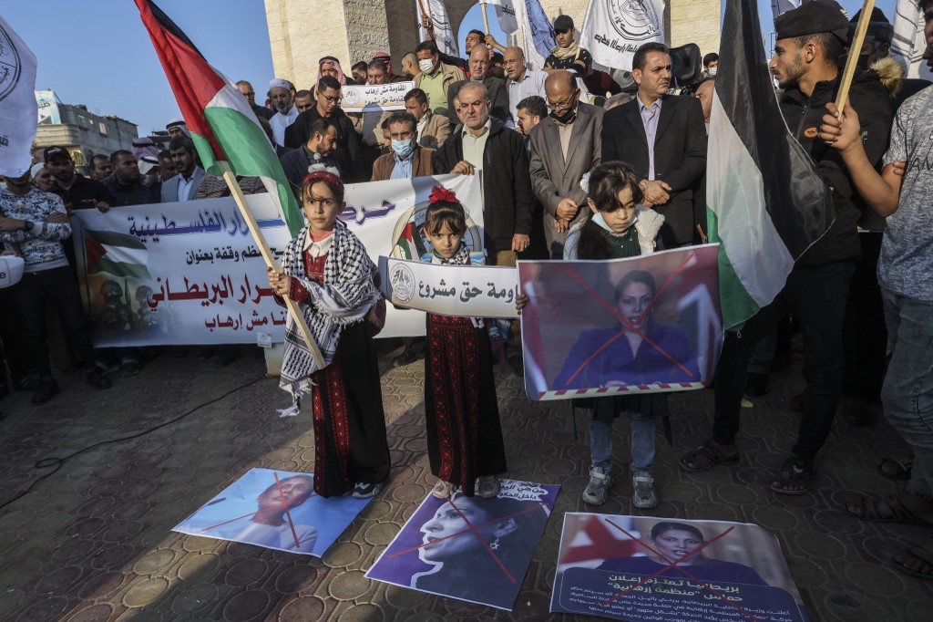 Palestinians hold posters depicting the crossed-out face of Britain's Home Secretary Priti Patel, in Rafah in the southern Gaza Strip, 23 November 2021 (AFP)