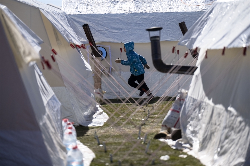A child runs amid tents at the Sumerevler Athletics Track, turned into a tent city for quake survivors on 16 February 2023 (Anadolu Agency)