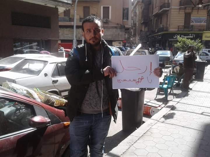 Ahmed Mohy holds a sign reading "Step down Sisi" before being arrested (Social media)