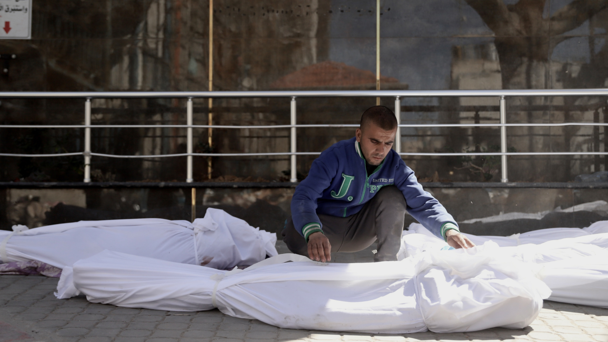 Un homme à l’hôpital al-Chifa examine les linceuls après l’attaque (Mohammed al-Hajjar/MEE)