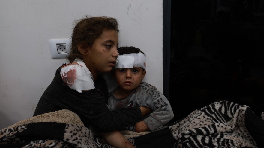 Wounded Palestinian girl Somay al-Najar comforts her brother Yamen following Israeli bombardments over Rafah in the southern Gaza Strip on 12 February, 2024 (AFP)