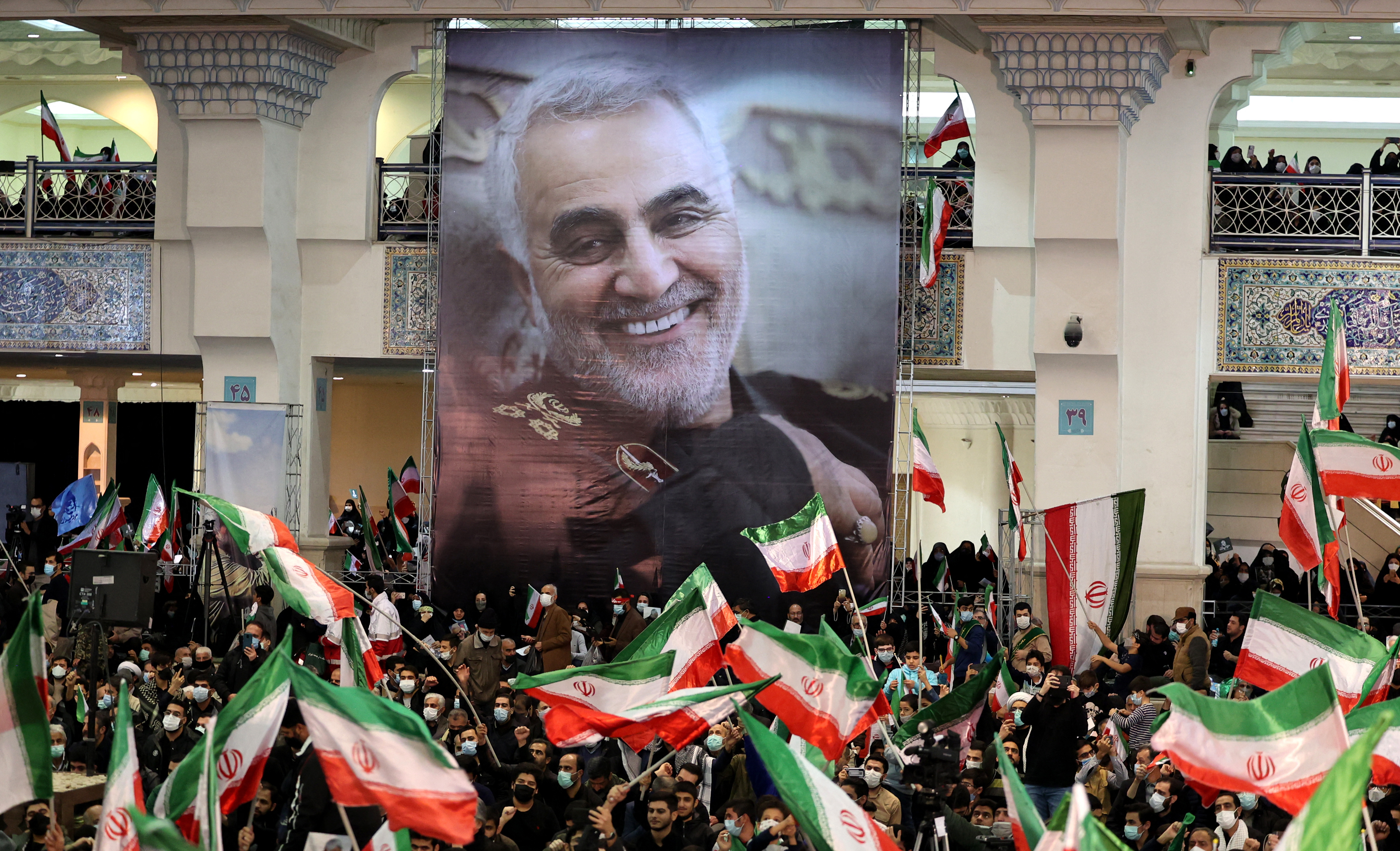 Iranians lift national flags during a ceremony commemorating the second anniversary of the killing of top Iranian commander Qassem Soleimani in Tehran on 3 January 2022 (AFP)