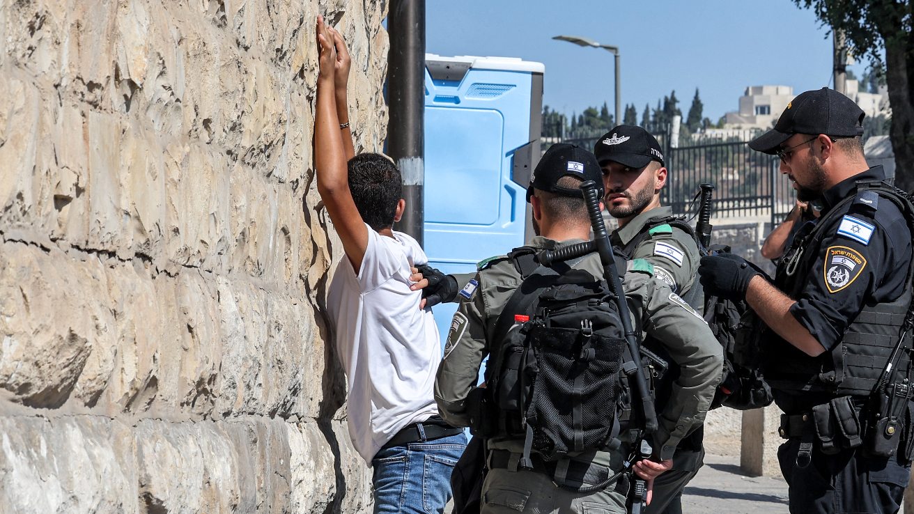 Des membres des forces de sécurité israéliennes fouillent un jeune palestinien à l’entrée de la porte des Lions vers la vieille ville de Jérusalem, le 13 octobre 2023 (AFP)