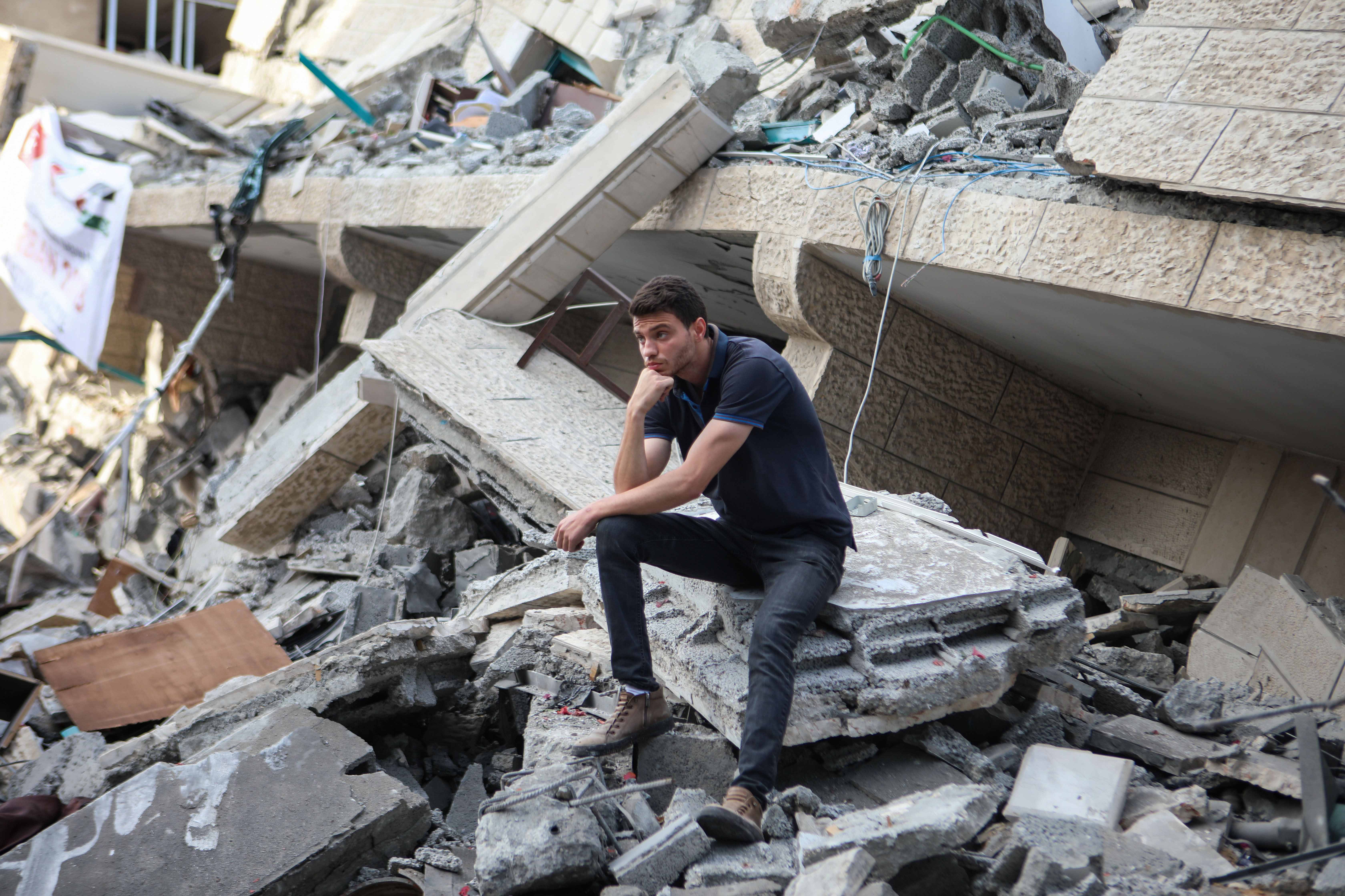 A Palestinian sits on the rubble of a building destroyed by an Israeli air strike in Gaza (MEE/Mohammed al-Hajjar)