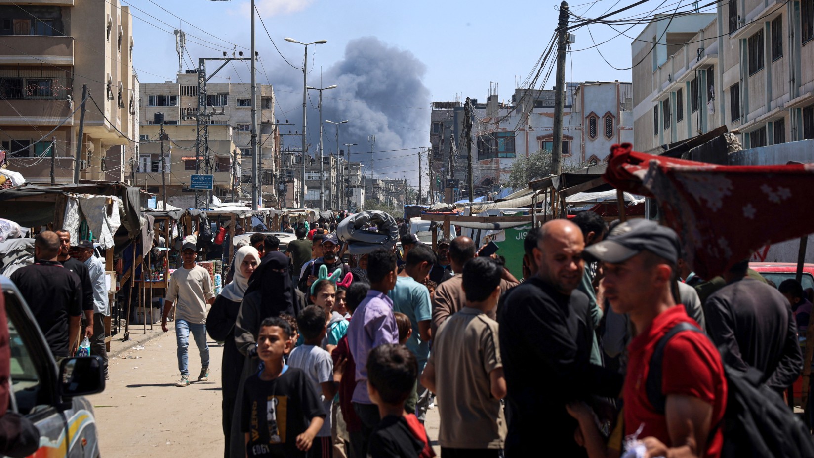 Palestinians crowd a street as smoke billows from Israeli strikes in Rafah in the southern Gaza Strip, on 7 May 2024.