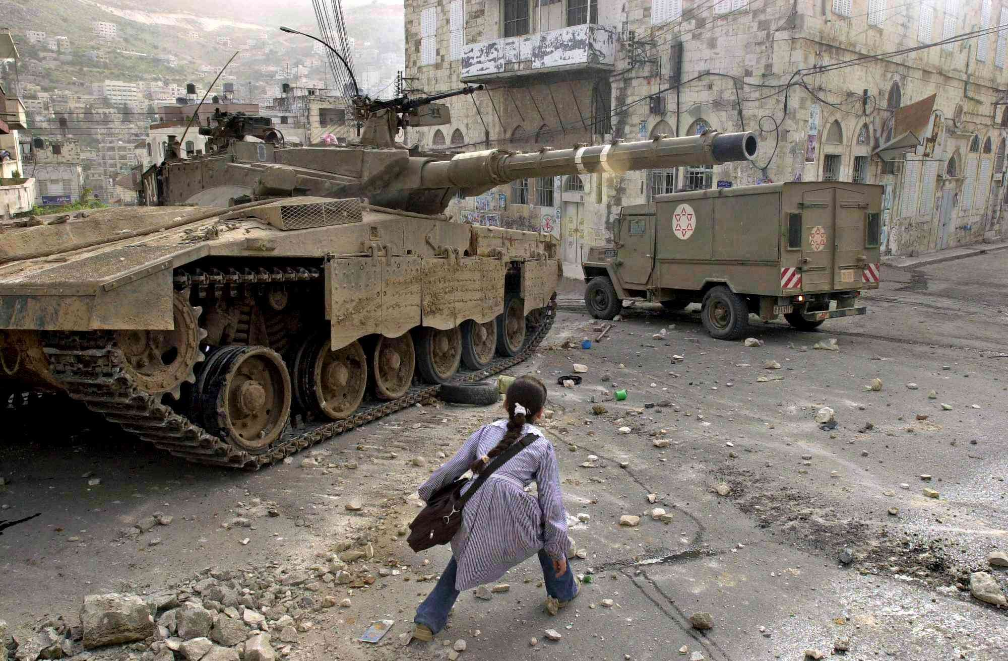 A girl creeps past an Israeli tank in Nablus in April 2003 in this photo by Nasser Ishtayer (AP)