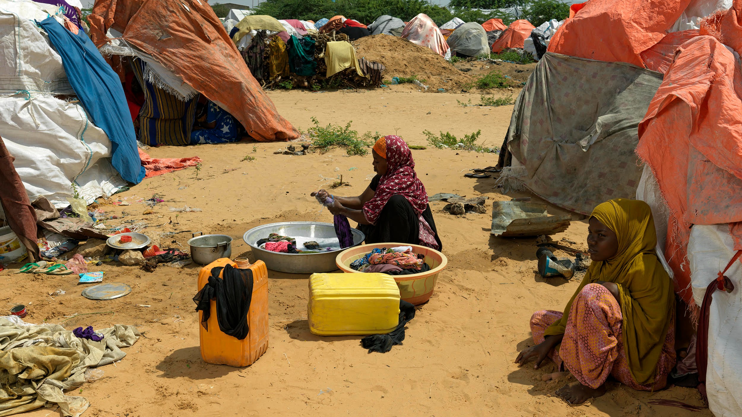 A woman washed clothes for internally displaced Somalis at a makeshift camp near the capital Mogadishu (MEE/Peter Caton)
