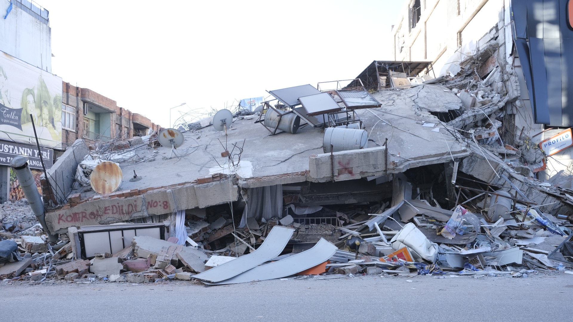 People walk on a street past a damaged building, after the 7.8-magnitude earthquake which struck parts of Turkey and Syria, in Adiyaman on 15 February 2023 (MEE/Ibrahim Gokhan Altindirek)