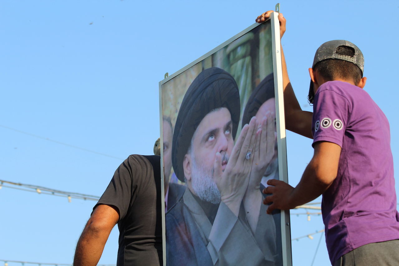 Protesters hold up a portrait of Muqtada al-Sadr in the centre of Tahrir square (MEE/Alex MacDonald)