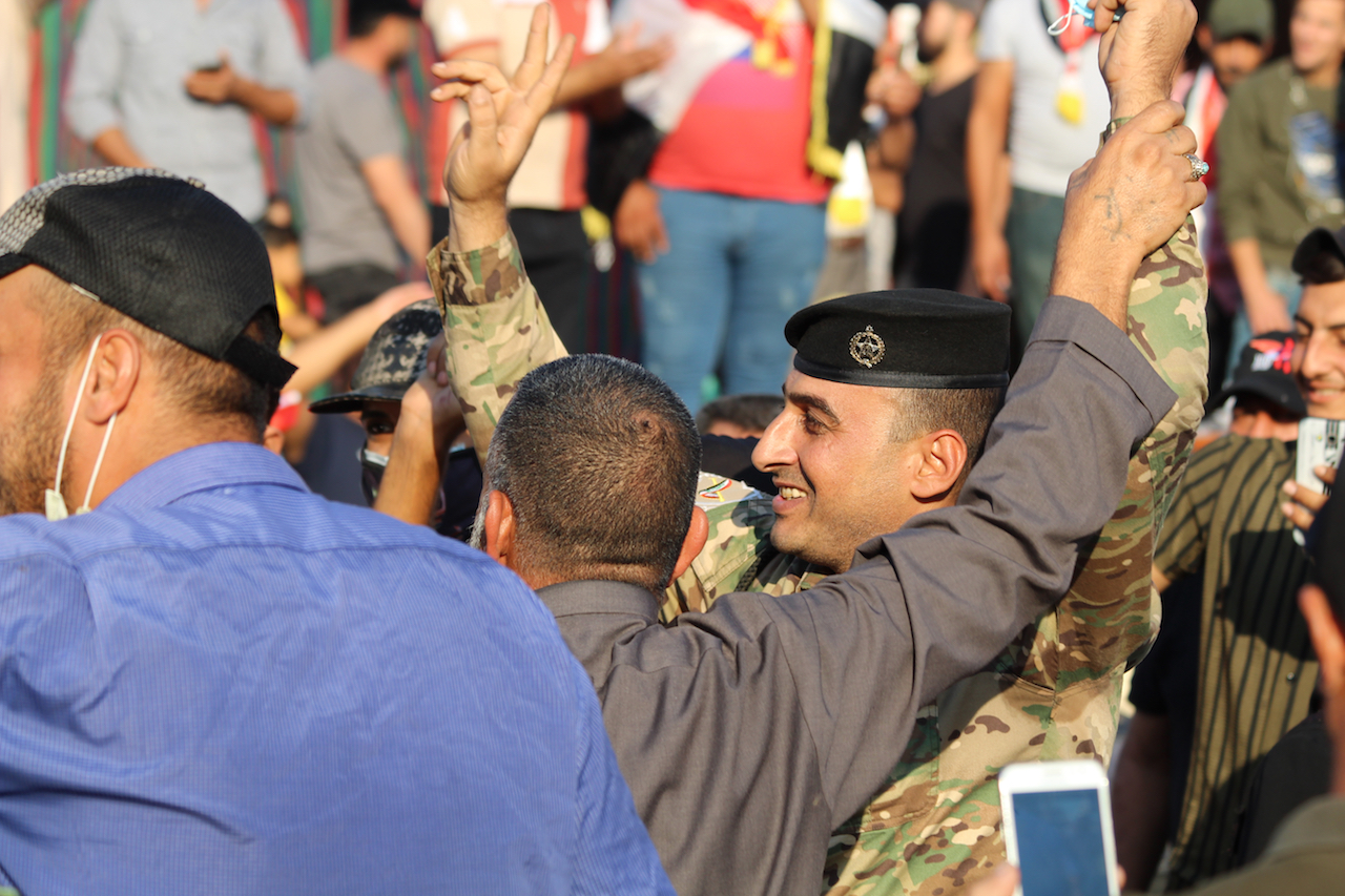 A member of the security forces dances with protesters in Tahrir Square (MEE/Alex MacDonald)