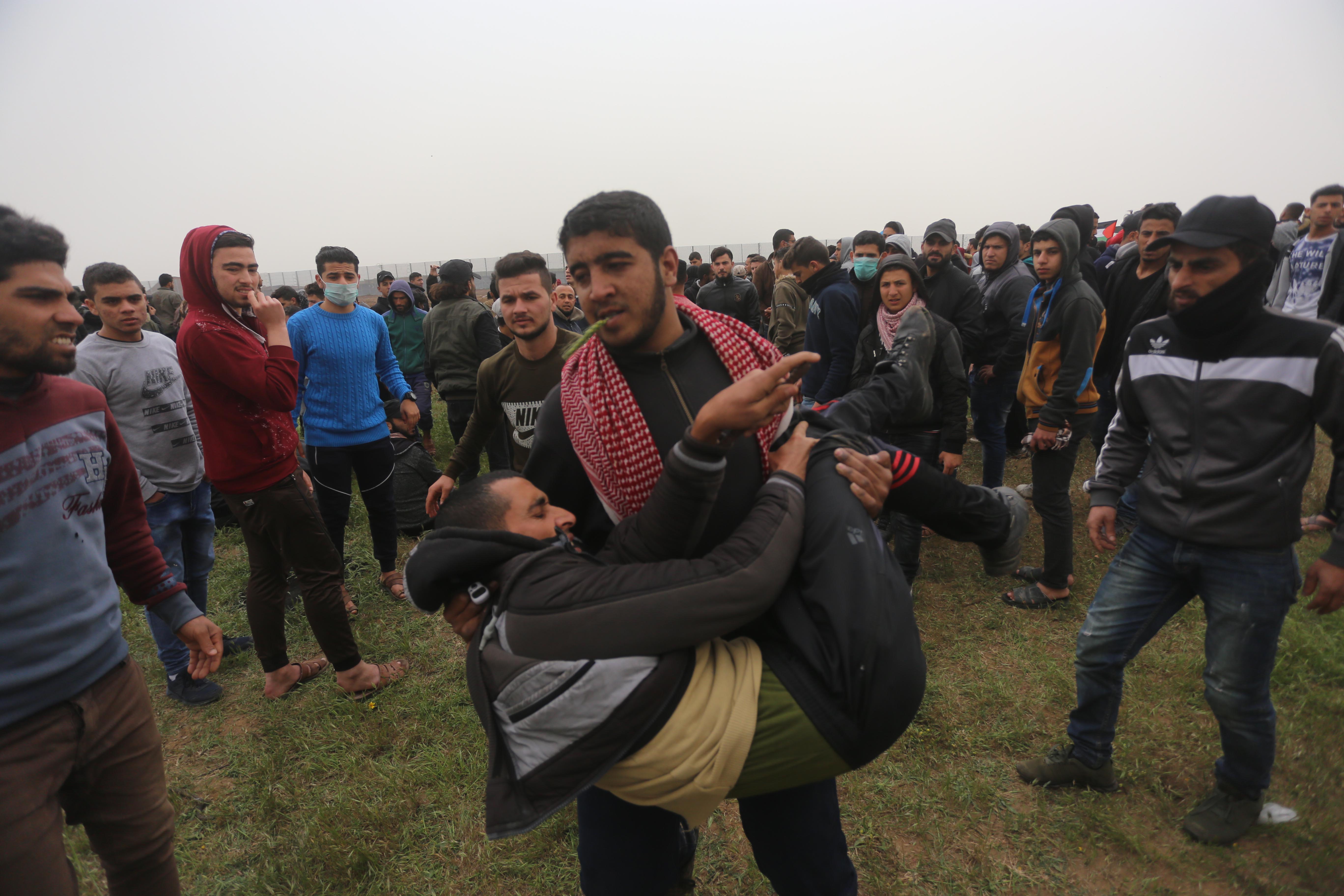 A Palestinian man carried a wounded protester to safety in the Gaza Strip (MEE/Mohamed Asad)