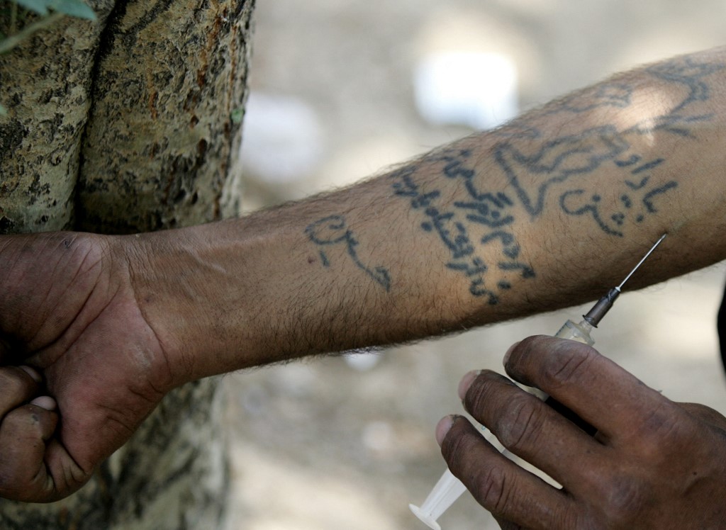 Javad, 45, an Iranian drug addict who used to be a truck driver, injects himself with heroin at a park in a working class neighbourhood in southern Tehran, 28 June 2006. 