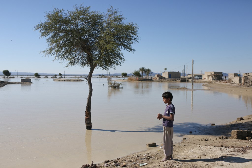 An Iranian youth stands in front of a flooded area in Dashtiari village in Iran's Sistan and Baluchistan region