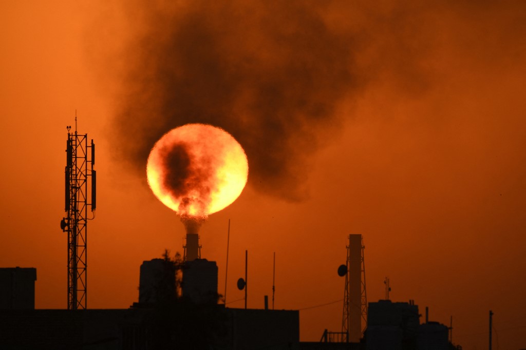 The sun sets over an oil refinery in southern Iraq on 8 March 2021 (AFP)