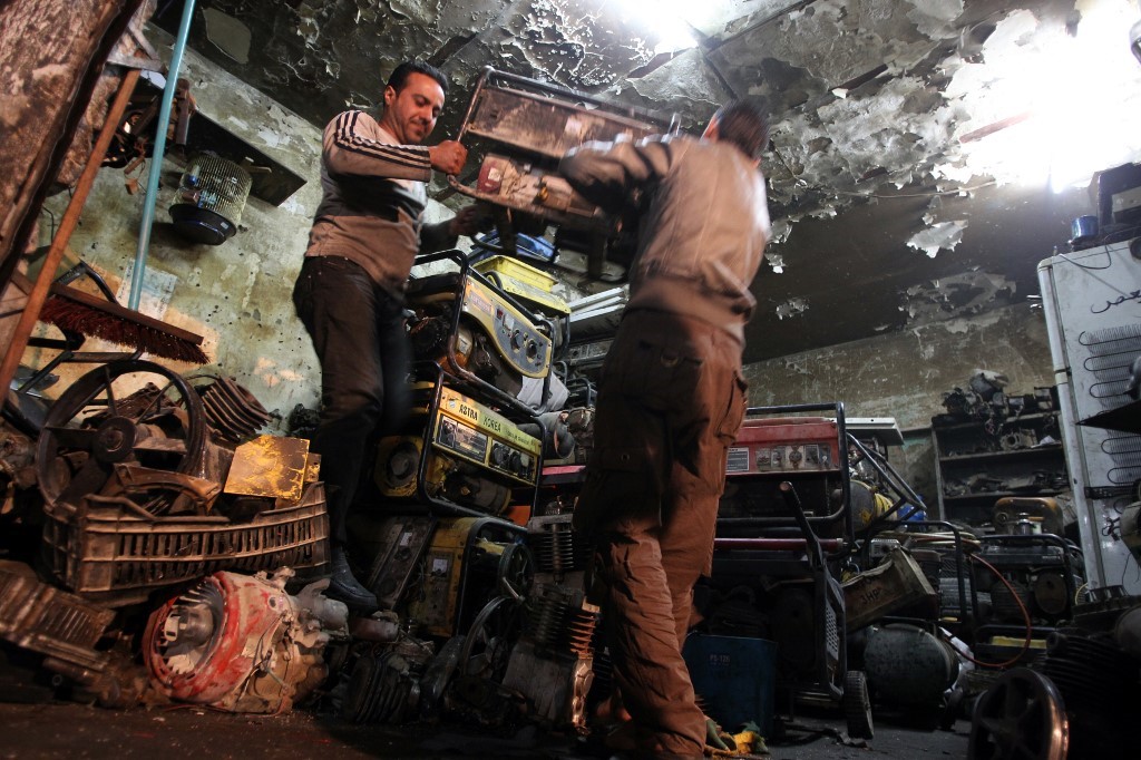 Des Irakiens transportent un groupe électrogène, souvent nécessaire pour fournir de l’électricité en raison des fréquentes coupures de courant, dans leur magasin de Bagdad le 19 mars 2014 (AFP)