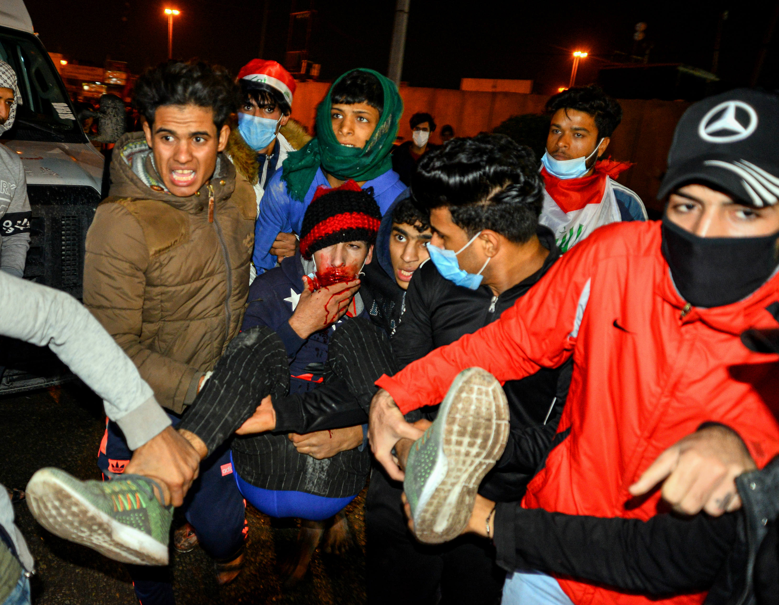 Iraqis carry away an injured anti-government protester during clashes with security forces in Najaf (AFP)