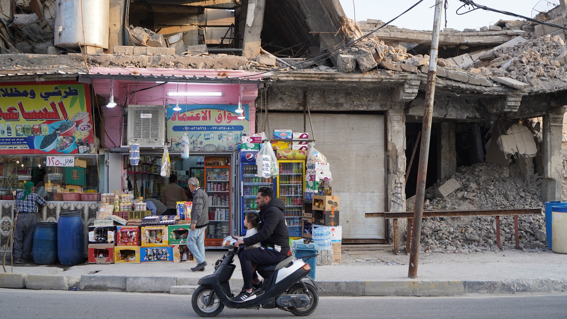 Un Irakien passe en scooter devant des bâtiments détruits il y a plusieurs années lors de la bataille contre le groupe État islamique, le 20 mars 2023 à Mossoul, dans le nord de l’Irak (MEE/Ismael Adnan)