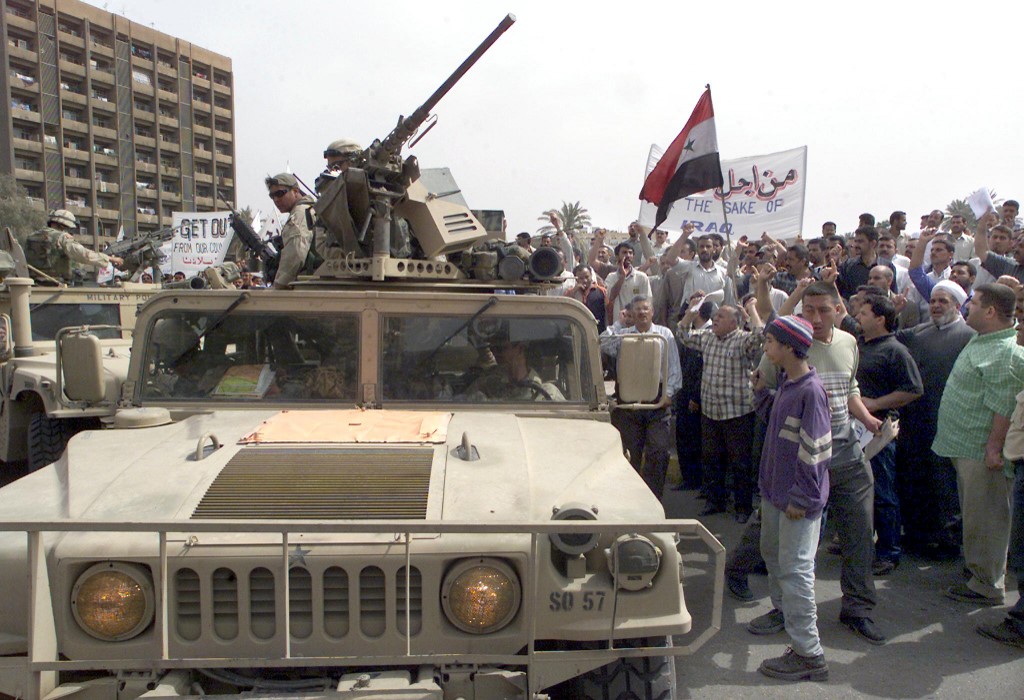 Iraqi protesters shout anti-US slogans as they surround military vehicles in 2003 in Baghdad (AFP)