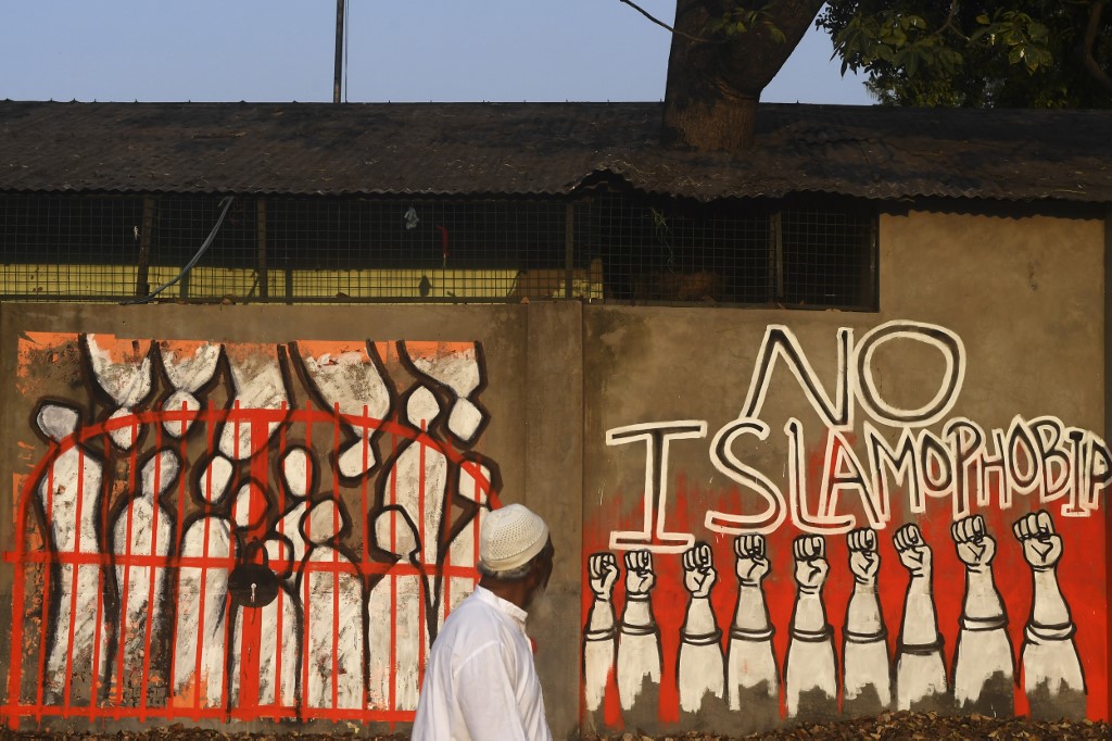 A man walks by a wall protesting Islamophobia in Kolkata, India, on 14 February (AFP)