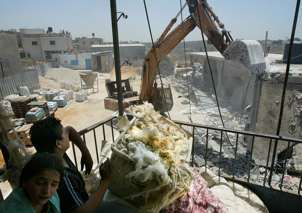 An Israeli bulldozer demolishes a Palestinian shop in the occupied West Bank in July 2004 (AFP)