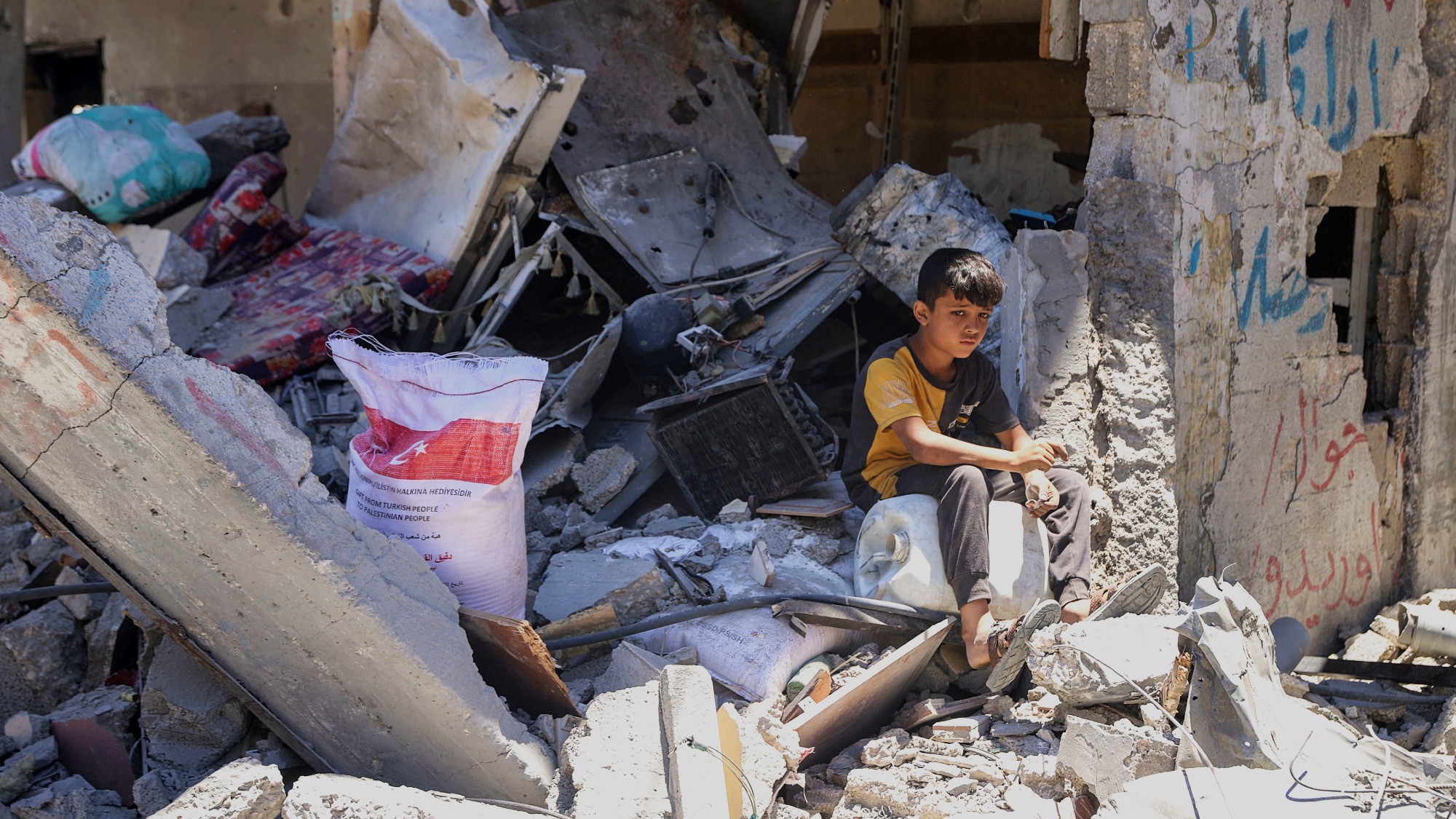 A Palestinian youth sits atop the rubble of a destroyed building in Jabalia refugee camp on 30 May 2024 (MEE/Enas Rami)