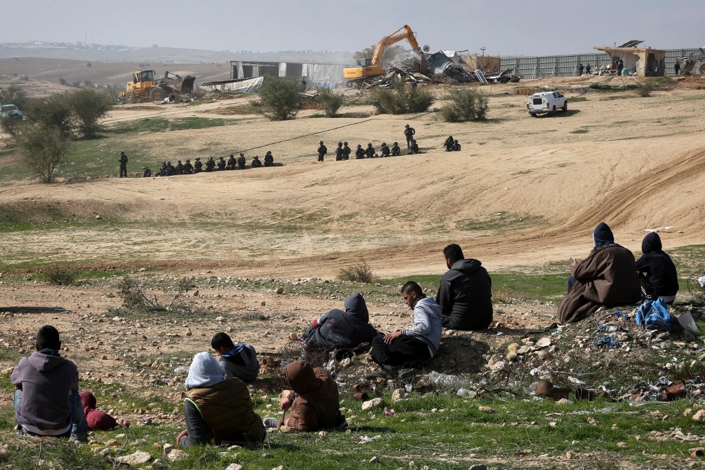 Israeli policemen stand guard as bulldozers demolish homes in the Bedouin village of Umm al-Hiran, which is not recognized by the Israeli government, near the southern city of Beersheba, in the Negev desert, on January 18, 2017.