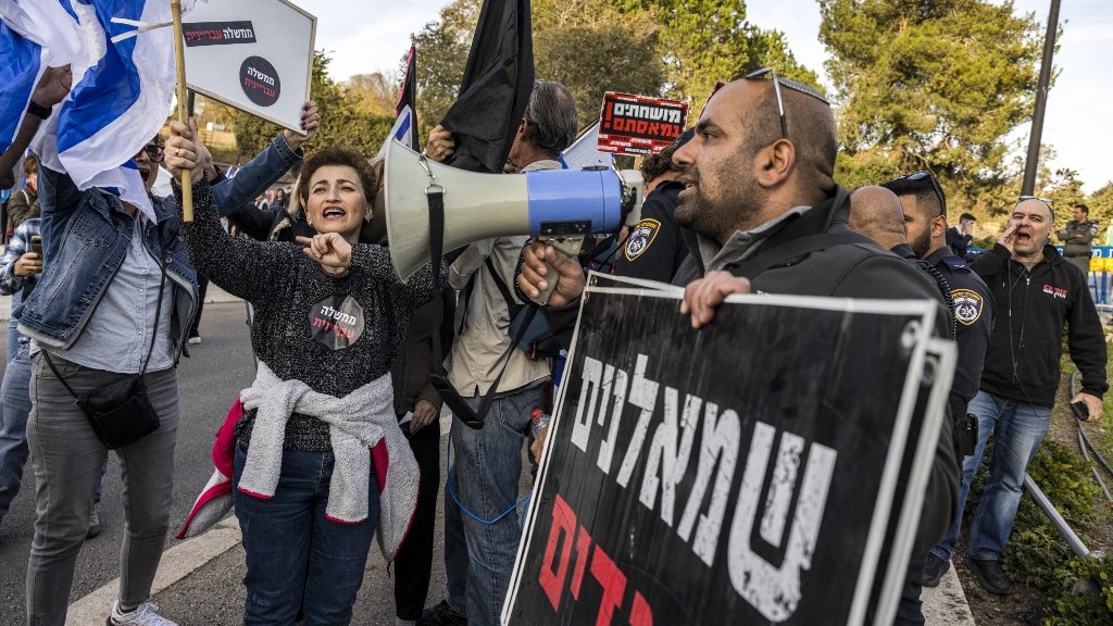A right-wing activist holds a sign reading “leftists traitors” during a protest by left-wing activists in Jerusalem on 12 December 2022 (AFP)
