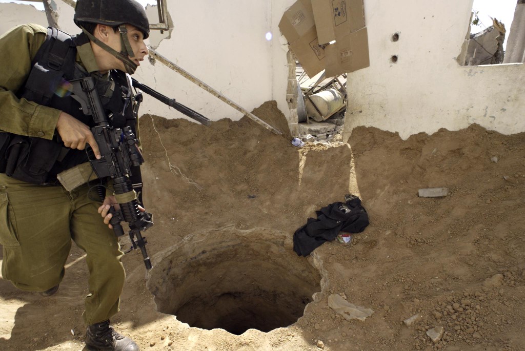 An Israeli soldier walks past the entrance of a large "smuggling tunnel" in a demolished Palestinian home in the southern Gaza Strip town of Rafah 22 May 2004 (AFP)