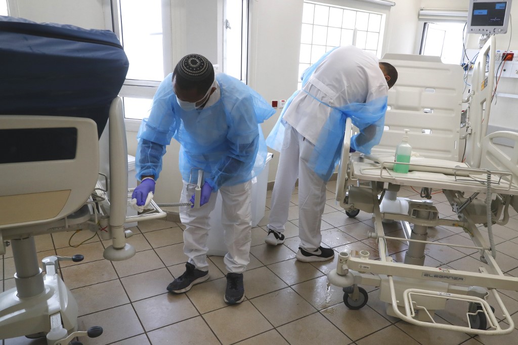 Medical staff clean and disinfect a hospital segment dedicated to Covid-19 patients in Tel Aviv on 19 March (AFP)