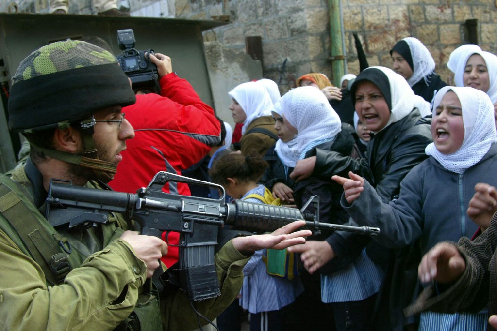 Palestinian students protest as an Israeli soldier points a gun in Hebron in 2005 (AFP)