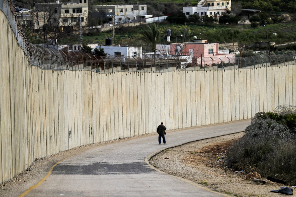 A man walks by Israel’s separation wall in the occupied West Bank on 1 February (AFP)
